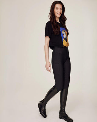 Full body walking pose featuring the black horse print tee and high-performance black riding tights.