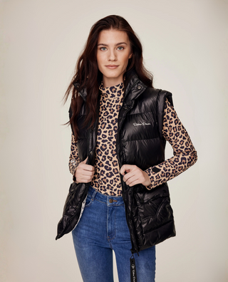 Frontvy i halvkropp av en modell som stylar Leo-ridtoppen under en svart pufferväst med original-riddenimbyxor.