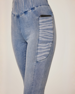 Angled front view of the light blue jeans breeches highlighting the decorative zebra print mobile pocket.