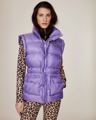 Modell som bär den lila ridvästen i pufferstil stängd med dragkedja, stylad med matchande leopardmönstrade ridbyxor.