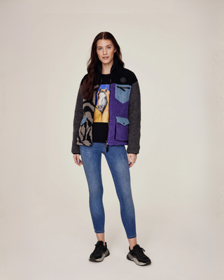 Helkroppsbild av en modell som bär en öppen lila jacka med zebramönster över en svart t-shirt och OG denimridbyxor.