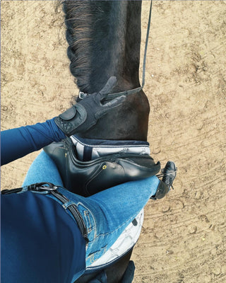 POV shot from the saddle showing a rider wearing original jeans breeches while horseback riding.