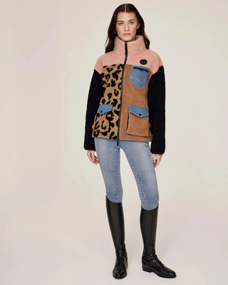 Full body shot of a model wearing the Pink and Leo teddy jacket paired with light blue denim riding tights.