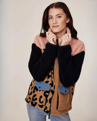 Modepose av en modell som visar teddyjackans unika färgblocksdesign i beige, leopard och rosa.