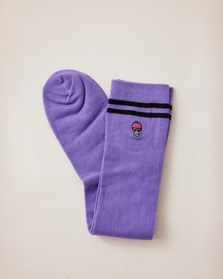 Pair of lilac riding socks neatly folded, showcasing the sporty black stripes and signature skull logo on the cuff.