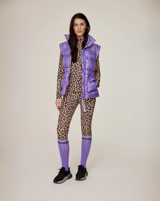 Full body front view of a model in a leo riding set and lilac puffer vest, styled with matching lilac equestrian socks.