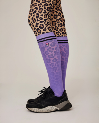 Close-up of a rider’s legs from the knee down, wearing leo riding breeches paired with lilac sporty socks and black skull detailing.