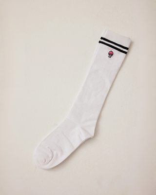 White knee-high riding socks with two black stripes and a small skull on the cuff, stretched to show length and fit.