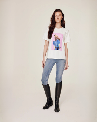 Full body shot of a model showcasing the white horse print tee and light blue jeans breeches.